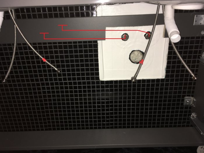 Installation av flexibel rördragning med fästen på en vägg bakom ett galler.