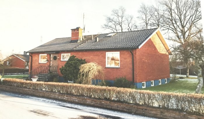 Liten tegelvilla från 1962 med nyinstallerade fönster och omgivet av en gräsmatta.