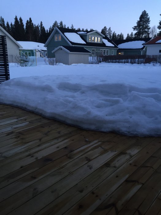 Vy från en träaltan med snödriva på 50 cm framför hus i Luleå i gryningen eller skymningen.