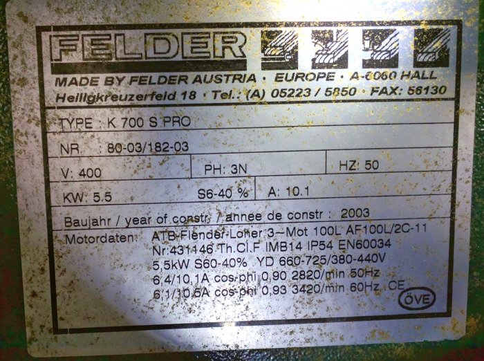 Smutsig märkskylt från en Felder träbearbetningsmaskin indikerar tekniska specifikationer och årsmodell 2003.