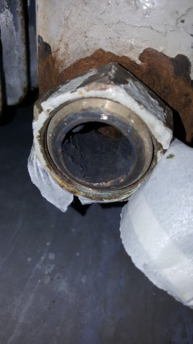 Närbild av en rördel med konformad anslutning täckt av rost och isolering.
