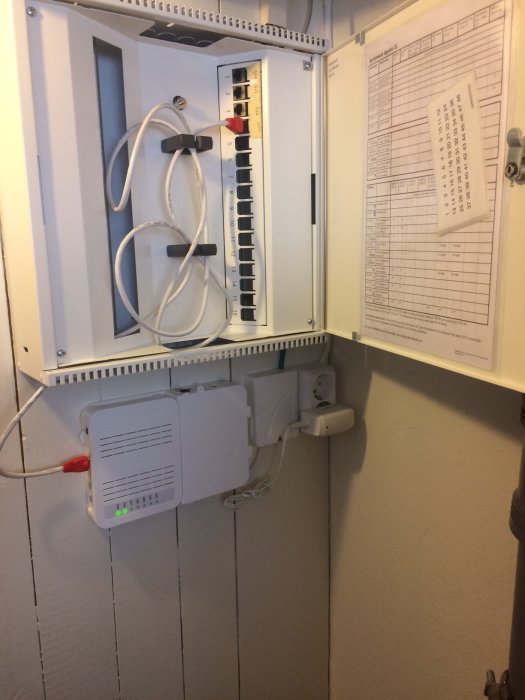 Nätverksskåp med patchpanel, Apple-router och dokumentation för hemnätverket.