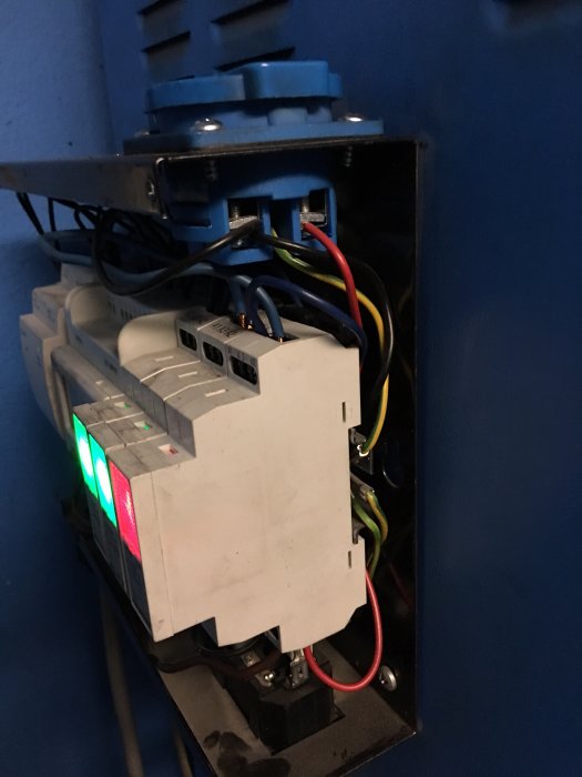Elektriskt relä monterat i skåp med synliga anslutningar och röd samt grön indikatorlampa.