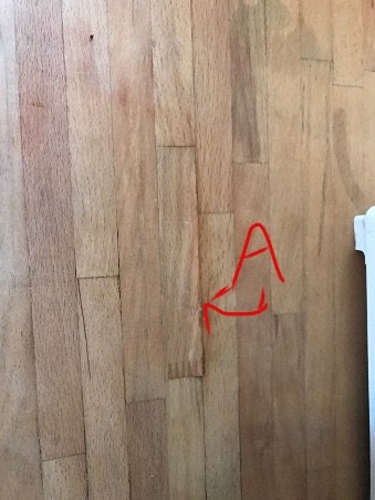 Träbänkskiva med fuktskada och röd markering vid skarven betecknad med "A".