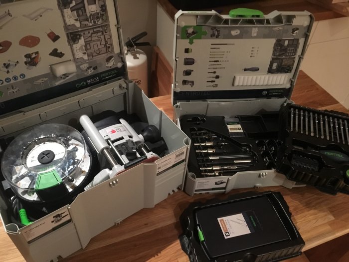 Öppnade verktygslådor med Festool-elverktyg och Centrotec-borrset på ett träbord.