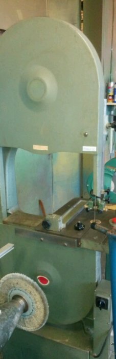 Grön bandsåg i ett verkstadsutrymme, eventuellt med självvässningsfunktion, enligt inläggets fråga.