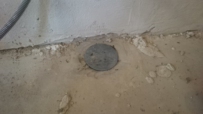 Ett igenpluggat avloppsrör i ett golv under renovering.