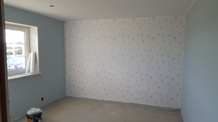 Nymålat barnrum med blå väggar och en tapetserad vägg med prickmönster.