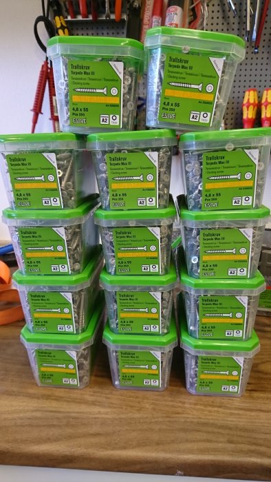 Stapel med gröna lådor av Essve trallskruv Torpedo Max III på en träbänk i en verkstad.