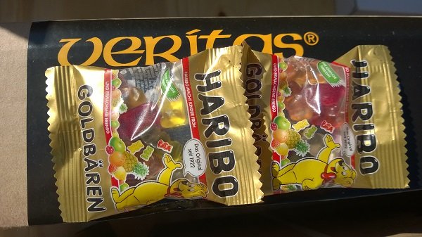 Tre förpackningar Haribo Goldbären gummibjörnar på ett bord, i solljus.