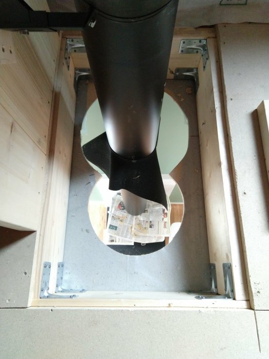 Steel angle brackets supporting a wooden frame around a black pipe installation.
