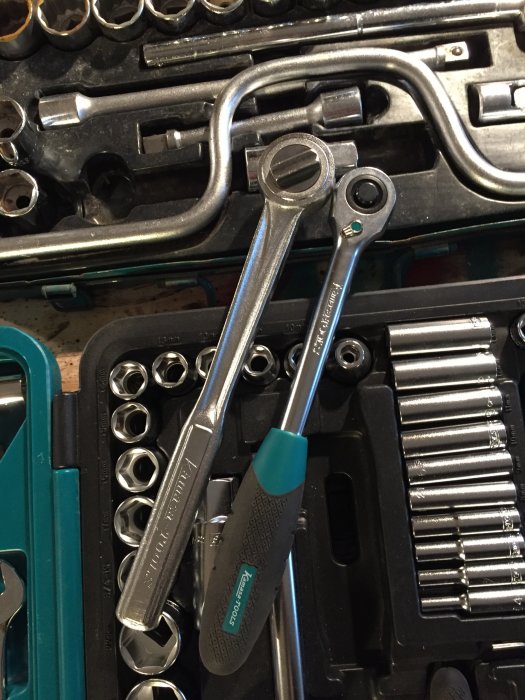Verktygslåda med olika nycklar och hylsor, fokus på en skiftnyckel och en hylsnyckel.