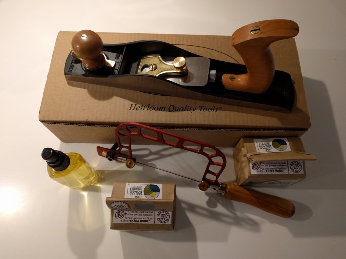 Lie-Nielsen jackhyvel LN 62, röd Knew Concepts 3" sticksåg, gul verktygsolja och paket med mjölkfärg på ett bord.