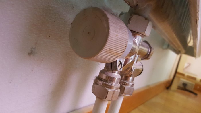 Gammalt termostatvred av plast som gått av, monterat på en klämkoppling från 70-talet.