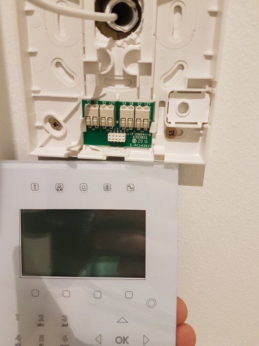 Öppen manöverpanel för hemmalarm med osammanhängd kabeldragning och oplacerad rökdetektor.