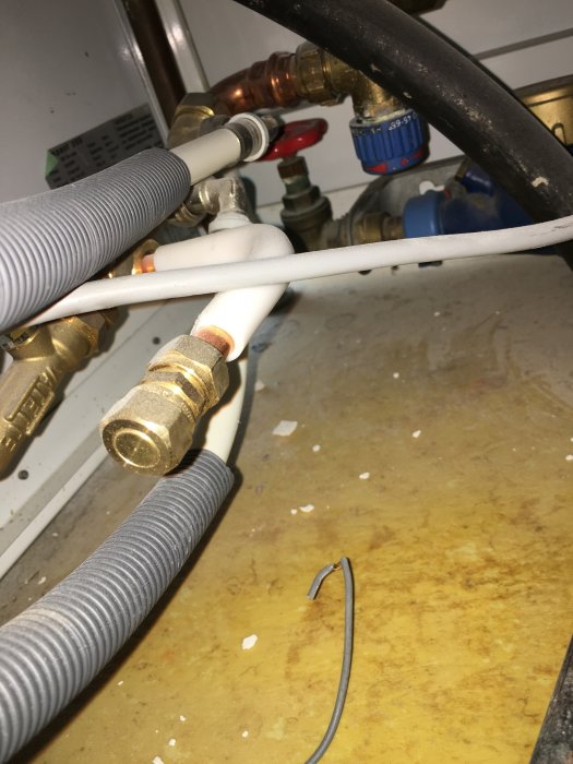 Klämringskoppling och prisolrör under installation nära andra VVS-komponenter och kablar.