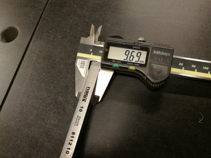 Digital skjutmått visar mätningen av en Narex-lockbettel på 9.69 mm mot en svart arbetsyta.