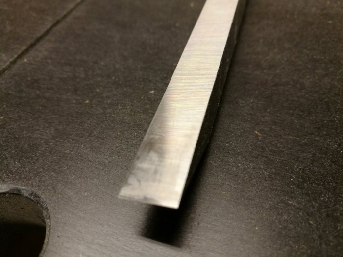 Närbild på ett polerat lockbettel på en mörk yta som visar sliprandiga ytor och skarpa kanter.