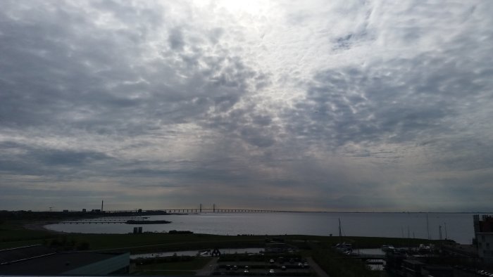 Utsikt över en bro och vattendrag med dramatisk molnig himmel.