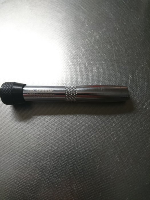 En screwfinder som används för att lokalisera skruvar ligger på en texturerad yta.