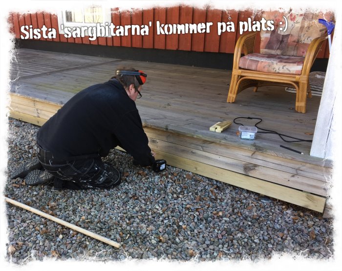 Person som monterar de sista plankorna på en träkant vid en uteplats.