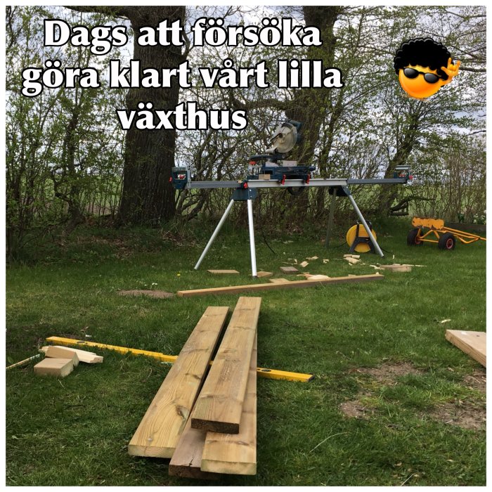 Renoveringsarbete utomhus med golvplankor, såg och verktyg på gräsmatta för ett växthusprojekt.