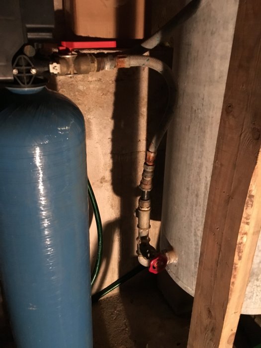 Vattenreningsutrustning med hydrofor, filter och rörinstallationer i ett pannrum.