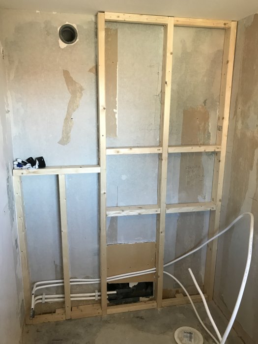 Skelett till vägg med 4-tums reglar, rördragning och förstärkning i en pågående badrumsrenovering.