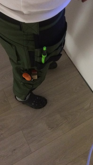 Nya gröna snickarbyxor från Lantmännen Ullared med verktyg i fickorna och crocs på fötterna.