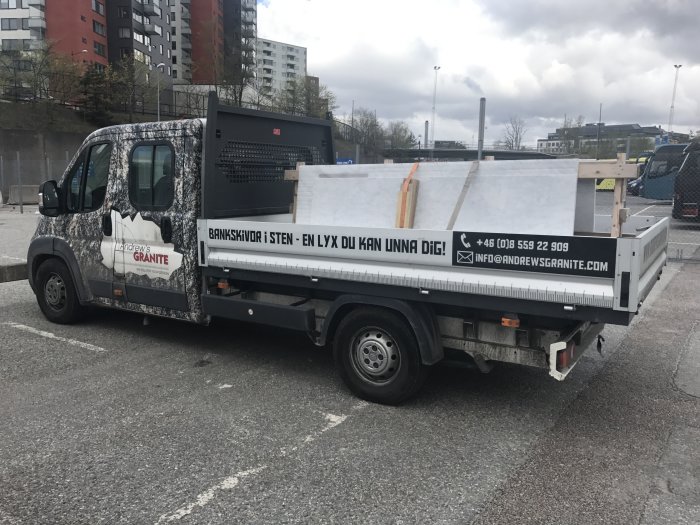 Lastbil med dekor av stenmönster parkerad i Frihamnen med reklam för granitföretag.