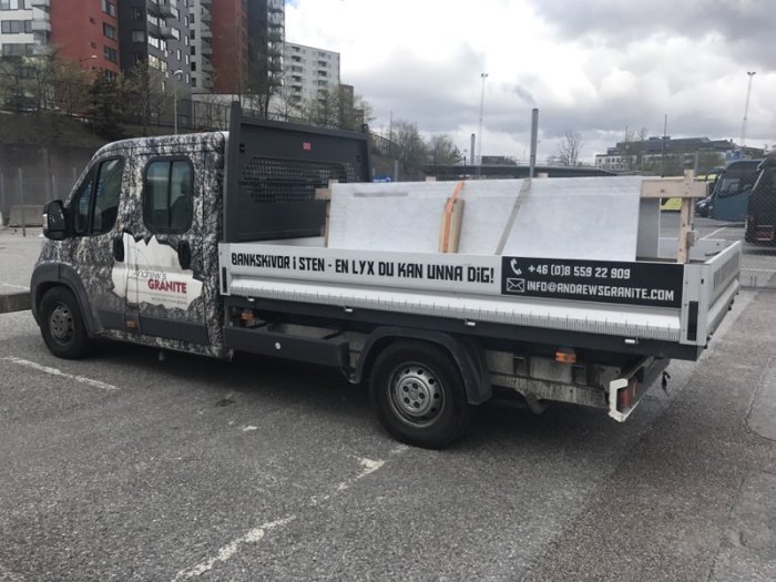 Lastbil med reklam för granit i Frihamnen, Stockholm, lastad med stenplattor.