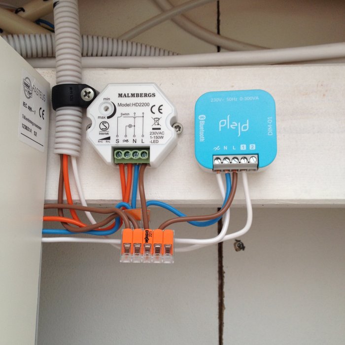 Installationsbild av Plejd dimmer i en kopplingsdosa bredvid en Malmbergs transformator, med synliga anslutna kablar.