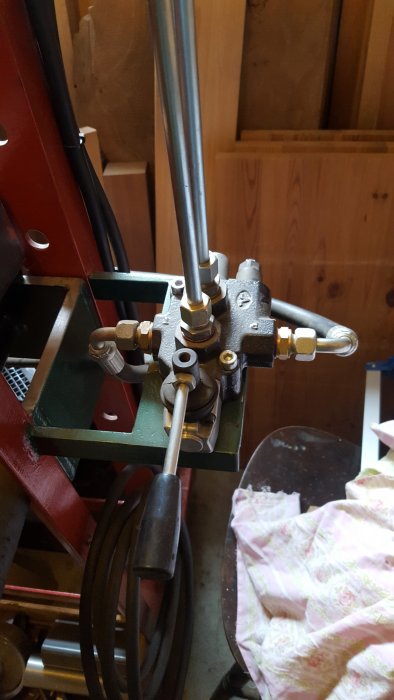 Närbild av en hembyggd hydraulpress med metallkonstruktion och slangar.