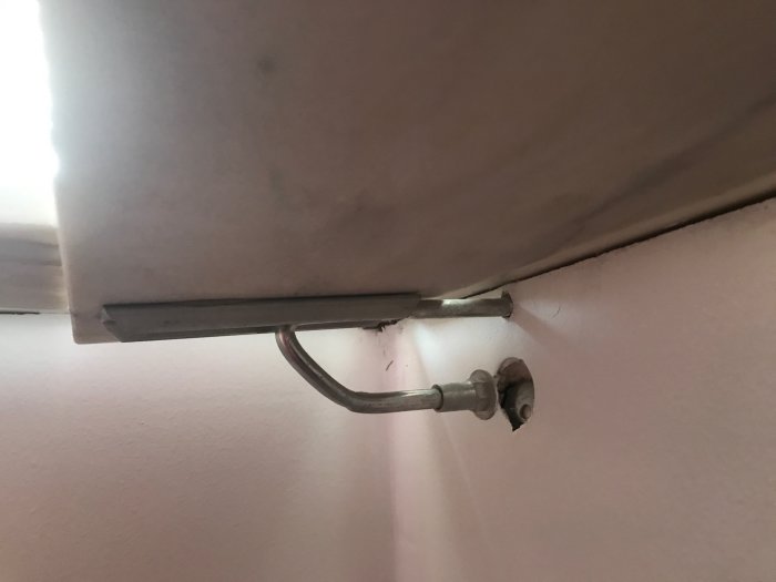 Infästning av fönsterbänk med metallkonsoll som har tryckt igenom en gipsskiva i väggen.