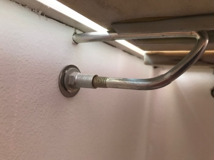 Konsollen under en fönsterbänk fastskruvad i en gipsskiva, närbild.