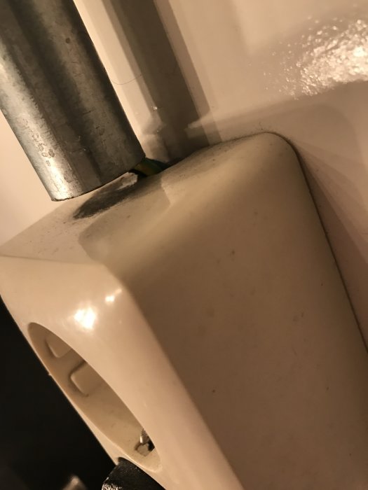 Flexibel koppling inuti ett metallrör vid toalettinstallation i en restaurang.