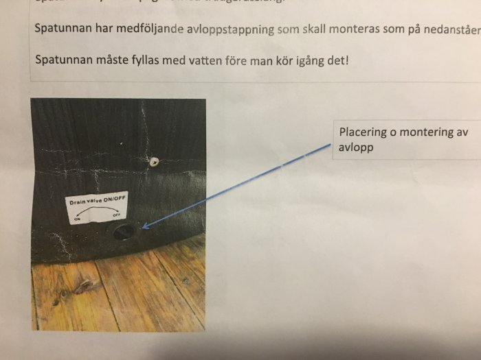 Svart badtunna med etikett 'Drain valve ON/OFF' och en pil som pekar på avloppsventilen.