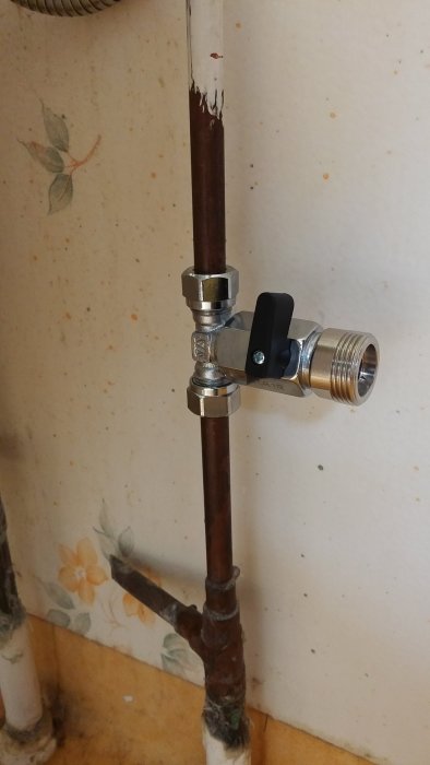 Nyinstallerad vattenventil på kopparledning mot vägg med tapet.