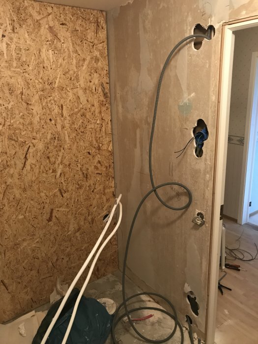 Renoveringsarbete med osb-vägg och elinstallationer inklusive uttag och kablar i ett rum under ombyggnation.