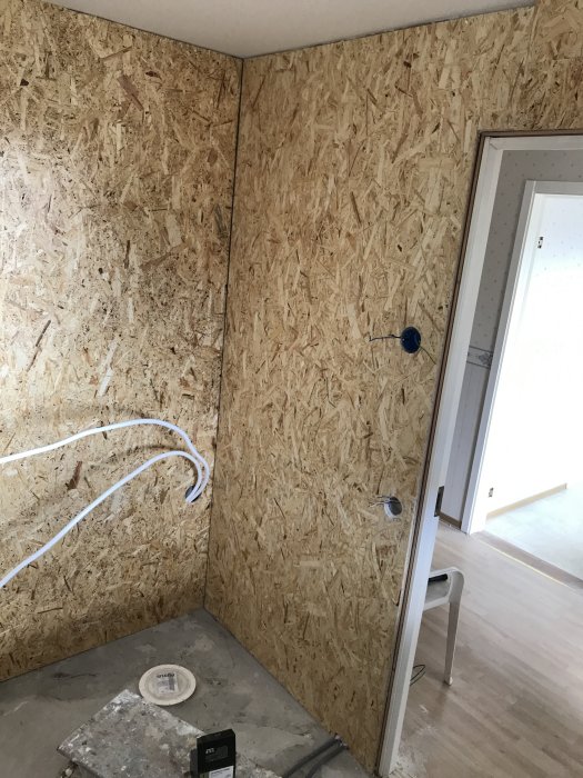 Renoveringsrum med OSB-väggpaneler och elinstallationer, inklusive utsatta kablar och väggdosor.