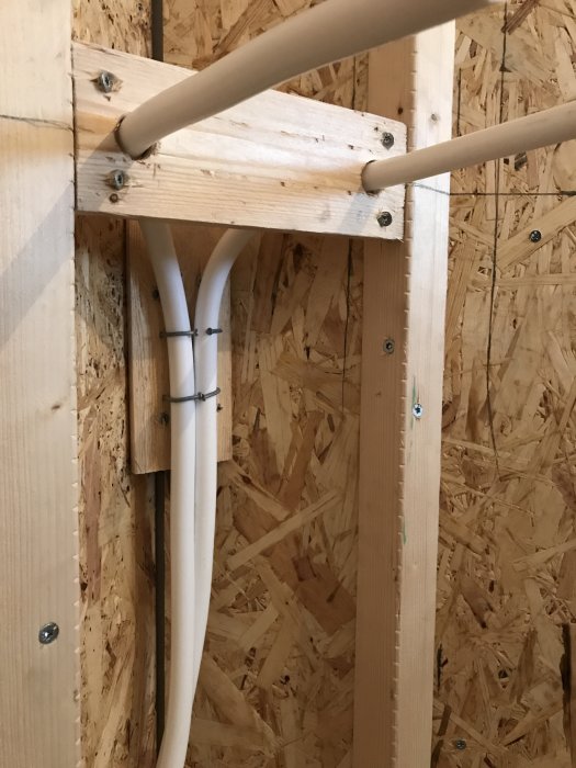 Elkablar och rör installerade i trästomme med OSB-skivor som bakgrund under renovering.