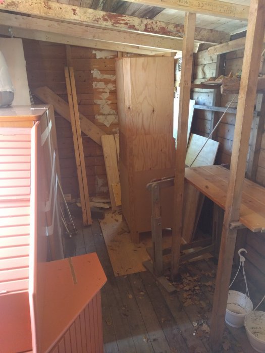 Inredning av en snickarbod med träbänkar, verktyg och oavslutade träprojekt.