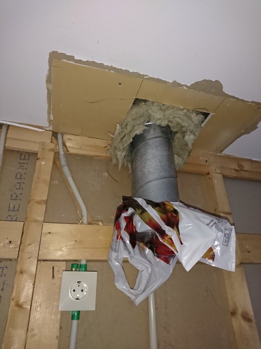 Renovering av kök med synligt isolerat ventilationsrör och öppet tak som förberedelse för fläktinstallation.