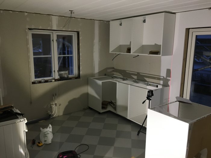 Kök under renovering med oskruvade gipsskivor och köksskåp delvis monterade.