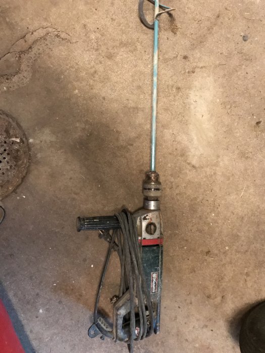 Begagnad Metabo blandare för flytspackel med synliga slitage och elkabel, liggande på ett betonggolv.