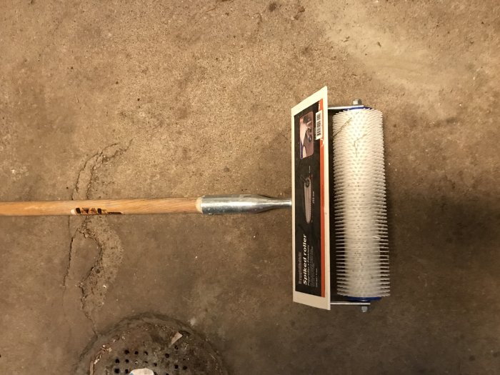 Piggroller för flytspackel med trähandtag, nästan ny, på betonggolv.