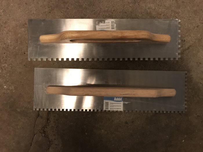 Två nya fixkammar med träskaft för byggbruk liggande på ett betonggolv.