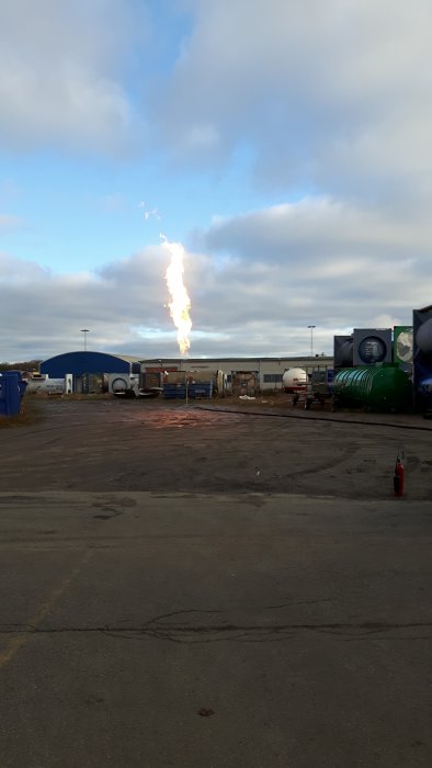 En stor låga på cirka 15 meter hög som flammar upp från en gasolbrännare på en industriplats.
