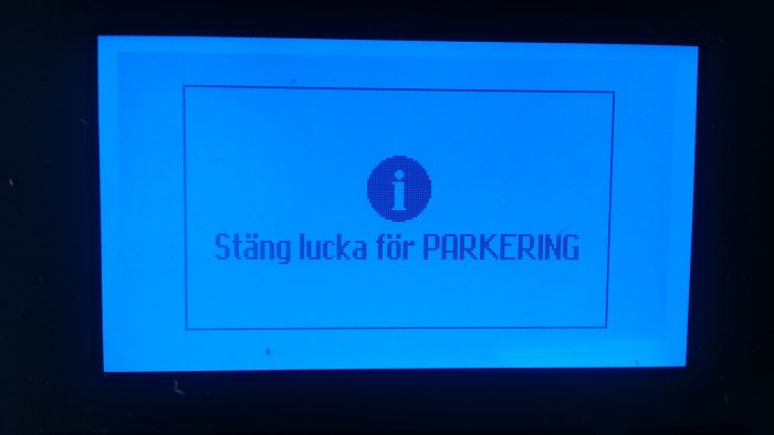 Digital skärm med texten "Stäng lucka för PARKERING" och en informationsikon.