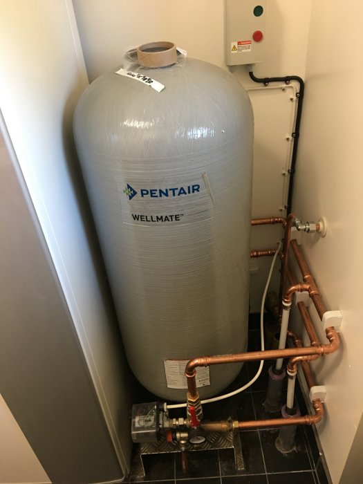 Installation av en Pentair Wellmate tank med kopparledningar och ventiler i en hushållsmiljö.